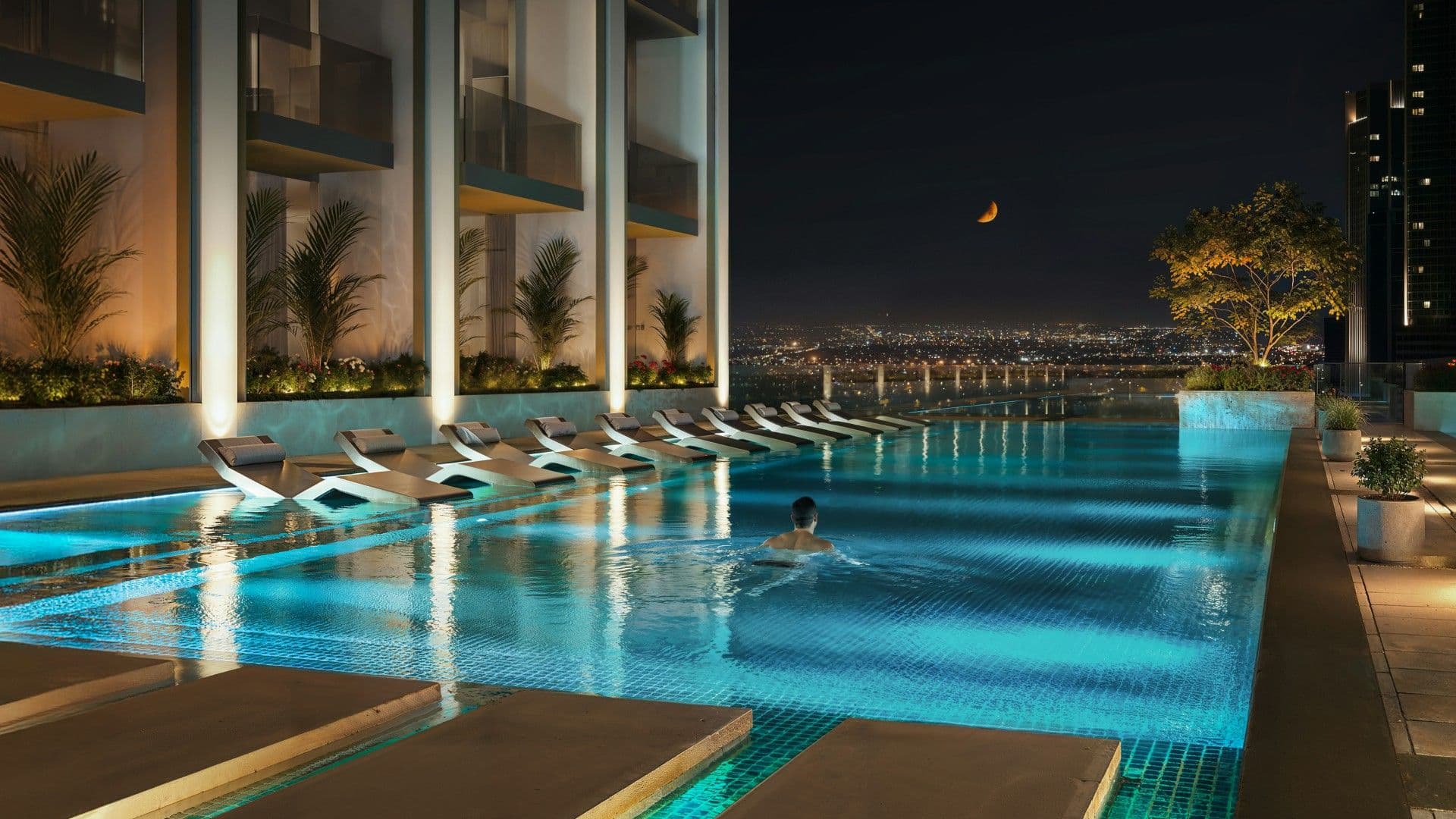 Swimming pool and sun loungers on the Binghatti Etherea amenity deck at night