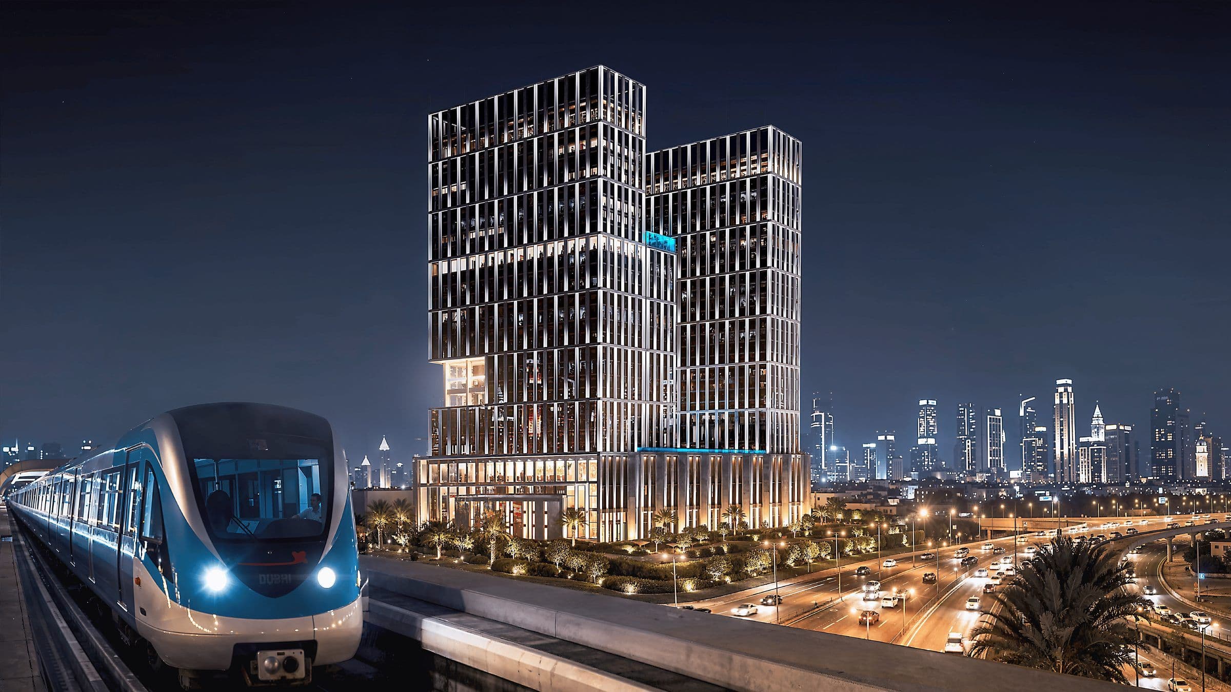 Binghatti Spectre towers at night beside the Dubai Metro line